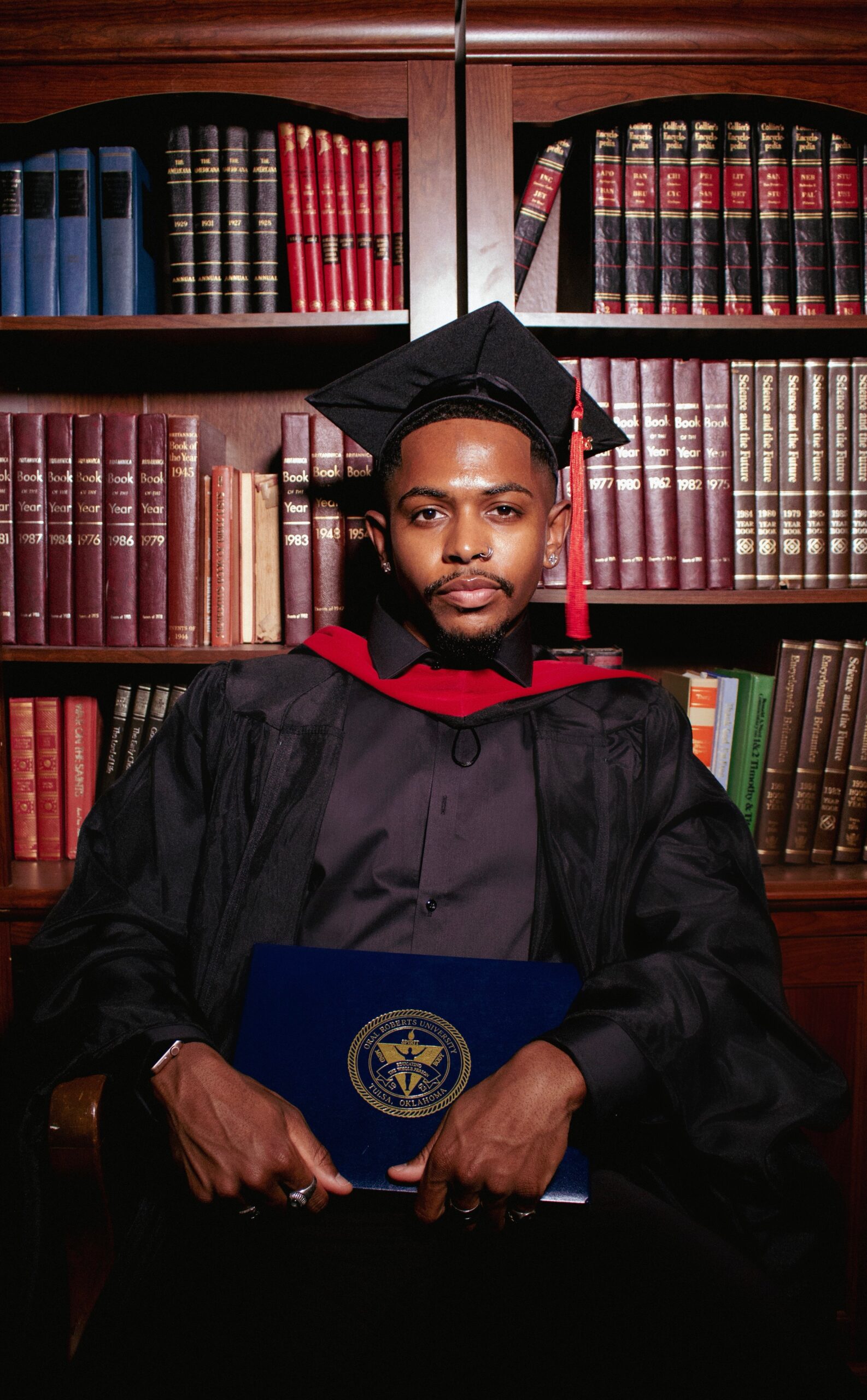 Jay in graduation cap and gown holding his diploma